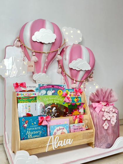 A full shot of the pink hot air balloon gift set, including the personalized bookshelf and a wrapped gift.