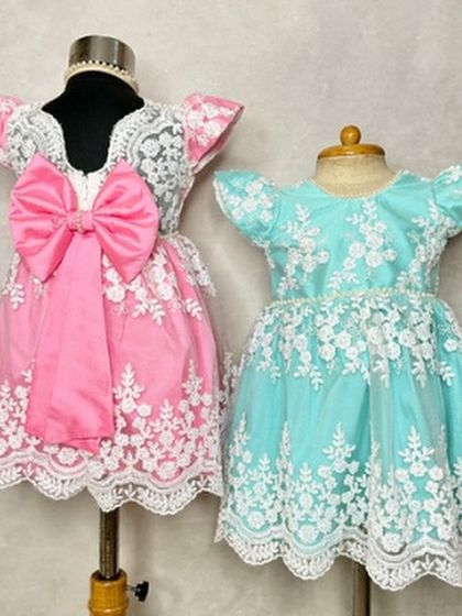 The "Arya" dress in two beautiful shades. Whether you prefer the playful pink or the cool aqua, this design with its intricate lace and flutter sleeves is a client favorite.