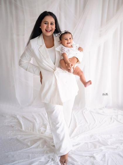 A happy mother holding her baby girl. Their matching white outfits are simple and beautiful.