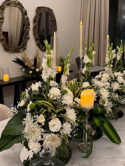 The dining table set for a housewarming party. We created lush centerpieces with white flowers and greenery, surrounded by candles to create an intimate and elegant dining experience for the family and their guests.