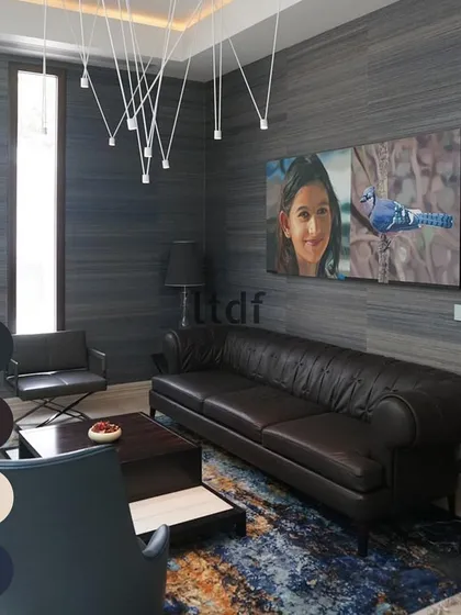 This moody and sophisticated living space uses a palette of deep blues and blacks to create an intimate atmosphere. The textured wallpaper adds depth, while the abstract, colorful artwork provides a striking contrast and a point of visual focus.