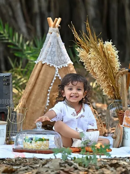 A wide shot of the beautiful picnic setup, complete with a teepee, teddy bear, and delicious treats.