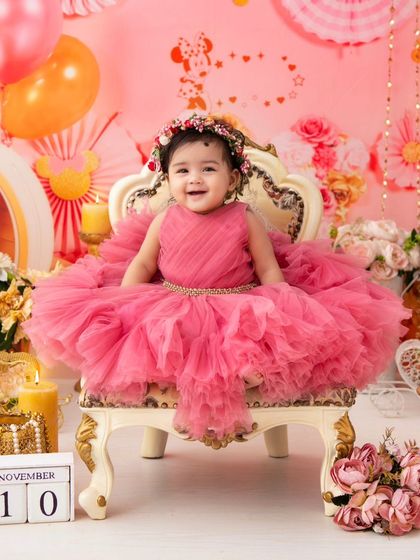 A princess celebrating her first birthday. The elaborate pink setup, complete with a carriage and candles, creates a true fairy tale scene.