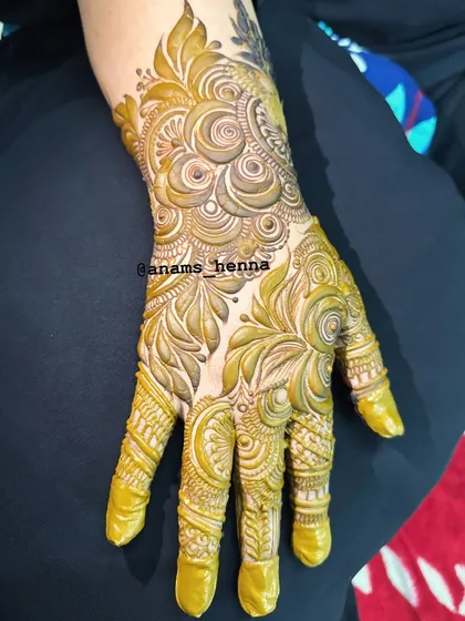 This full-hand design is inspired by Gulf henna art, with its characteristic bold lines, shaded florals, and intricate finger details.