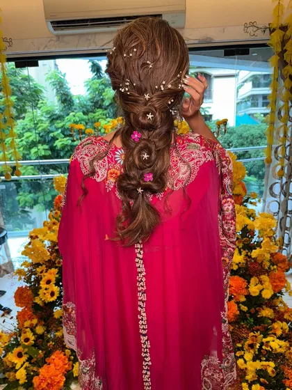 A whimsical and romantic braided hairstyle, perfect for a fun Mehendi or Haldi ceremony. I wove in delicate star and pearl accessories with pops of pink flowers to match the bride's vibrant outfit.