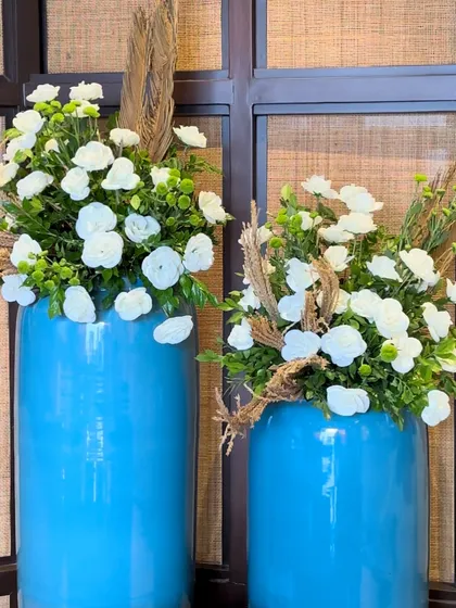 Bright blue vases provide a pop of color, filled with white flowers and dried grasses. We love playing with color and texture to create unique decorative moments.