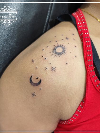 A beautiful celestial tattoo on the shoulder, featuring the sun, moon, and a sky full of stars.
