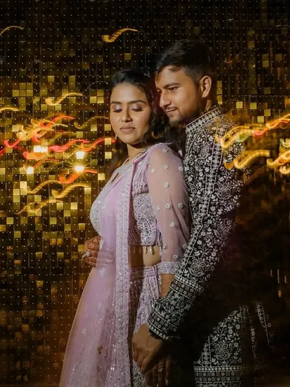 An abstract couple portrait using slow shutter speed to create dynamic light trails against a glittering gold background. This technique adds energy and a celebratory feel to sangeet photos.