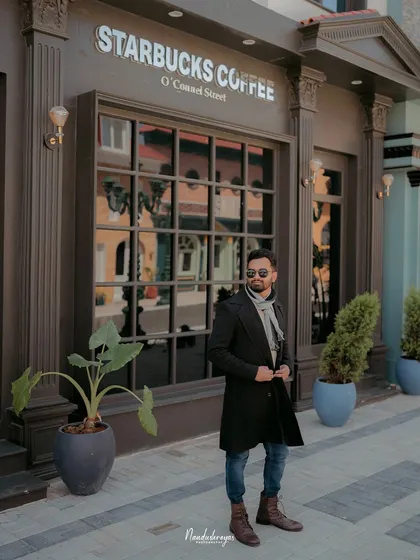 A solo portrait of the groom looking stylish in front of an urban cafe facade.