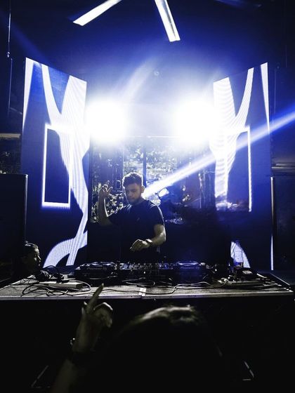 A wide shot showing the full effect of a custom visual setup at Raahi, with bright lights framing the large LED screen behind me.