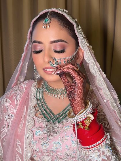 A detailed shot showing the intricate henna and the delicate nath. I ensure the makeup complements every element of the bride's attire and accessories.