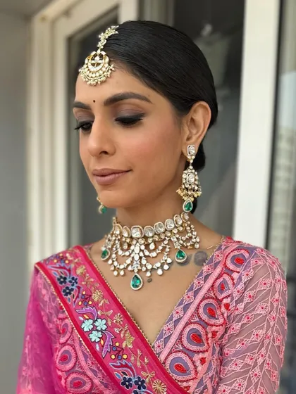 A front view of the client, showing how the sleek hairstyle perfectly complements her heavy traditional jewelry.