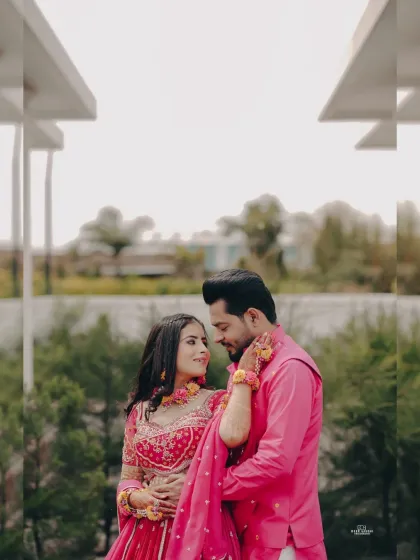 A beautiful portrait of the couple in their matching pink Haldi outfits. The floral jewelry and the outdoor setting add a fresh, romantic feel.