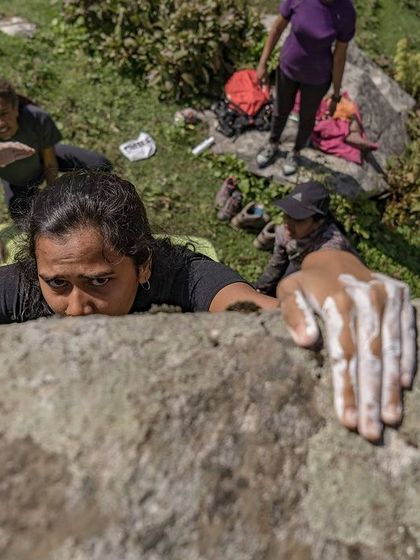 Chalked up and ready to go. A climber reaches the top of a boulder, showing the strength and focus she's built.