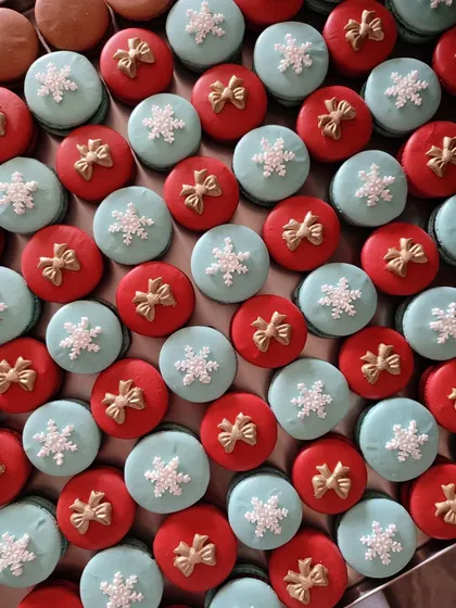 My Christmas macarons are a festive delight. This batch features red and light blue shells, decorated with tiny sugar bows and snowflakes, filled with a delicious ganache.