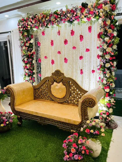 An elegant photo booth for a baby shower. This setup features a frame of multi-colored roses and hanging strings of jasmine and rose petals against a white curtain.