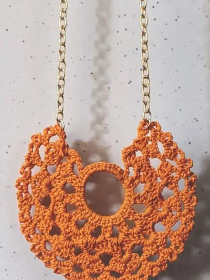 This vibrant orange lace pendant is perfect for adding a warm, artsy touch to your look. The intricate crochet pattern is lightweight and eye-catching.