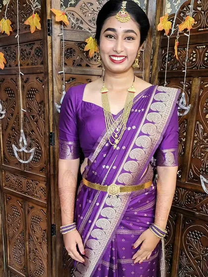The client looks happy and elegant in her perfectly draped purple saree. This style is a great example of modern ethnic wear.