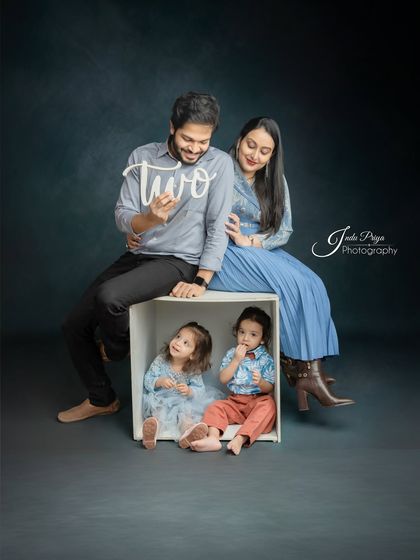 Celebrating a "two" big milestone. This family portrait captures the parents with their adorable twins, who are sitting in a box, for a pre-birthday photoshoot.