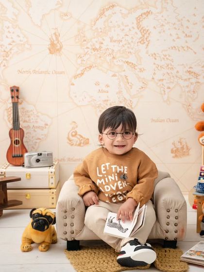 This little world traveler is ready to learn, surrounded by books, a globe, and a map of the world.