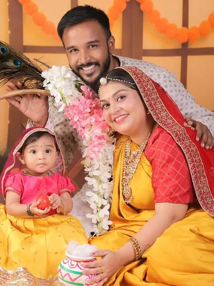 A beautiful family portrait celebrating their daughter's 8-month milestone with a Radha theme. The family is dressed in coordinated traditional attire.