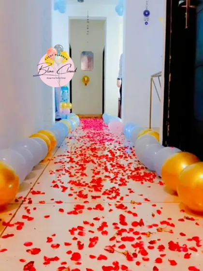 A romantic pathway decorated with rose petals and a line of white and gold balloons.