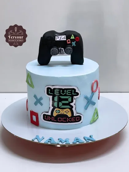 A PS4 theme cake for a 12th birthday. This Nutella chocolate cake features a fondant controller on top and the classic PlayStation button symbols around the side.