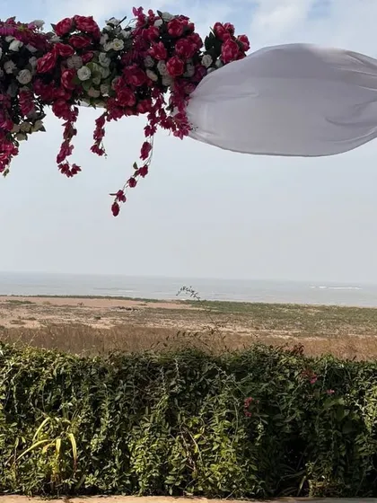 A simple yet stunning floral arch for a beachside wedding ceremony. The design frames the natural ocean view perfectly, creating a beautiful and serene setting for an intimate exchange of vows.