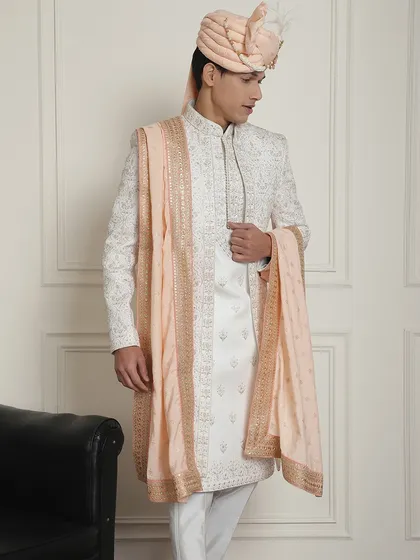 For your summer wedding, an ivory sherwani with a peach stole is a perfect choice. This outfit is made from lightweight fabric and features delicate embroidery, ensuring you stay comfortable while looking regal. I can customize the stole color to match the bride's lehenga.