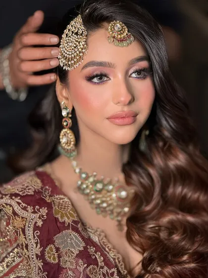 A close-up of the intricate details that go into a bridal look. Here, we're perfecting the placement of the passa. The makeup features soft, blended eyeshadow and a flawless base, creating a look that's both traditional and modern.