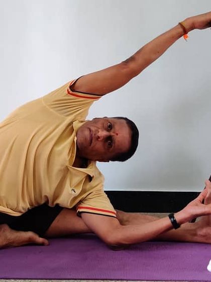 Parivrtta Janu Shirshasana using a chair. The chair provides a stable point to hold onto, allowing you to use leverage to rotate the torso and open the side of the body.