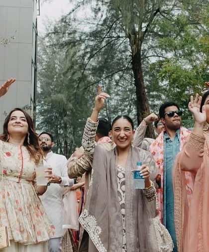 The baraat party arriving with full energy and dancing. We capture the fun and festive mood of the wedding procession against the lush greenery of the beach resort.