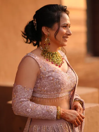 A candid, close-up shot of the bride's happy expression. This photo highlights her intricate gold necklace and the delicate sequin work on her blouse.