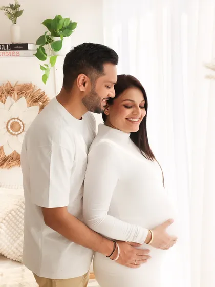 A beautiful couple portrait from a bright, airy session. His loving embrace from behind and their shared smiles create a feeling of warmth and happiness.
