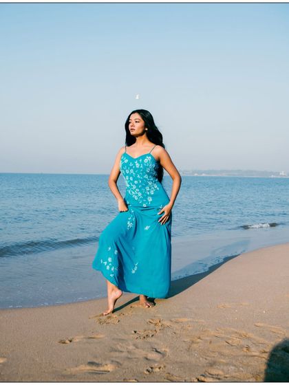 A classic, elegant pose on the sand. The model's posture is strong, and the long shadow adds a graphic element to the composition.