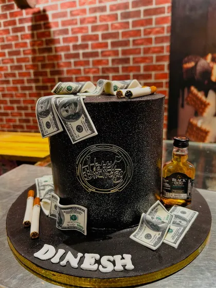 A sleek, black glitter cake for Dinesh, themed with edible money, fondant cigarettes, and a miniature bottle of Black Dog whisky.