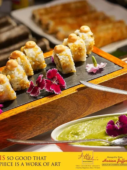 Our sushi is so good that every piece is a work of art. This platter displays beautifully crafted sushi rolls, garnished with edible flowers, alongside a vibrant green dipping sauce, showcasing our expertise in Japanese cuisine.