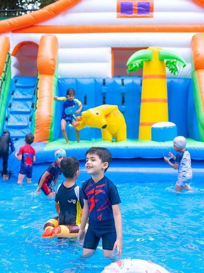 A wide shot of the inflatable play area, showing multiple kids enjoying the slides and pool simultaneously.