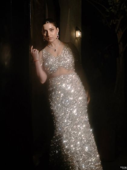 A glamorous portrait of the bride, Kajal, in her sparkling engagement gown. The dramatic lighting highlights her and creates a sense of star quality.
