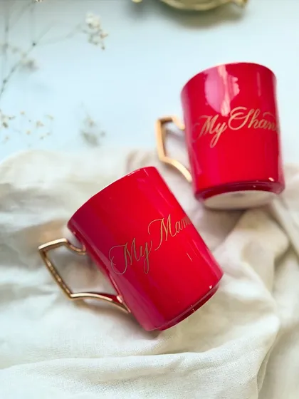 Bright red coffee mugs with gold handles, personalized with gold engraving. The contrast is striking and makes for a bold, loving gift.