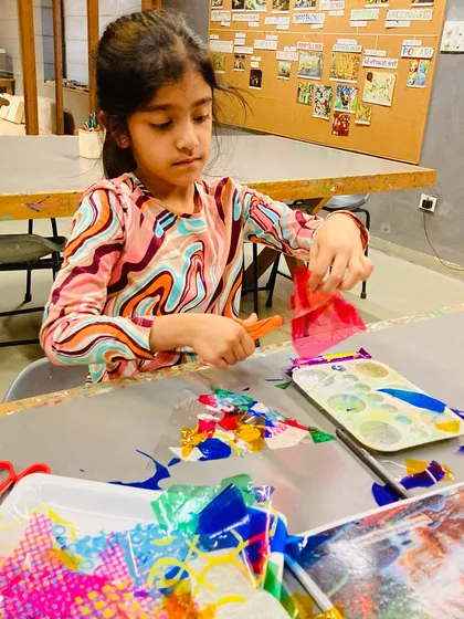 A student cuts colorful transparent sheets, preparing the materials for her lantern's mosaic-like panels.