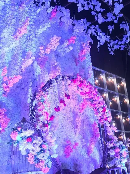 The same floral swing stage under dramatic blue lighting, showing its versatility for both day and night events.