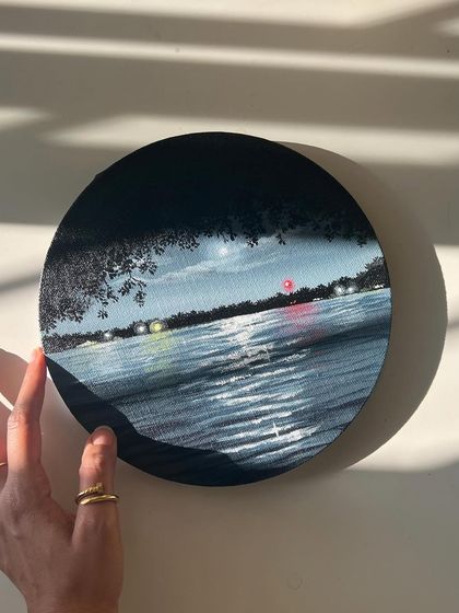 Holding the round nightscape painting, with the light creating beautiful shadows.