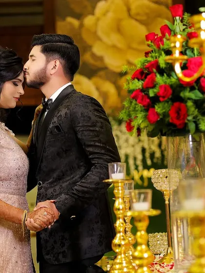 A tender forehead kiss amidst the beautiful decor of their engagement party. A truly romantic and heartfelt moment.