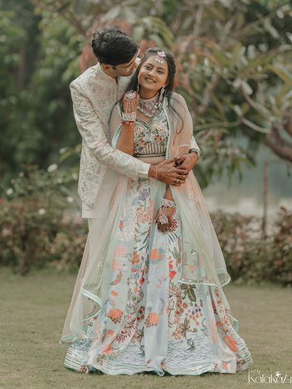 A playful and loving embrace in the garden. The groom's hug from behind and the bride's happy smile make this a heartwarming shot.