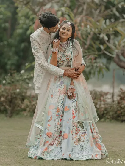 A playful and loving embrace in the garden. The groom's hug from behind and the bride's happy smile make this a heartwarming shot.