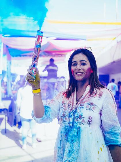 A guest unleashes a cloud of blue color at our rooftop Holi party. We provide high-quality, organic colors to ensure a safe and fun celebration for everyone.