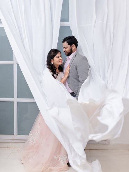 A dreamy and romantic portrait using flowing white curtains to frame the couple. This technique adds softness and a sense of intimacy to the shot.