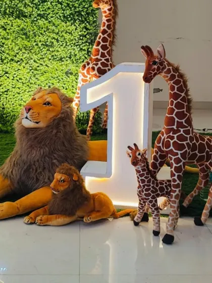 We also provide individual props for rent, like these large light-up marquee numbers and realistic animal figures. Here, a number '1' is surrounded by a family of lions and giraffes for a safari-themed photo op.
