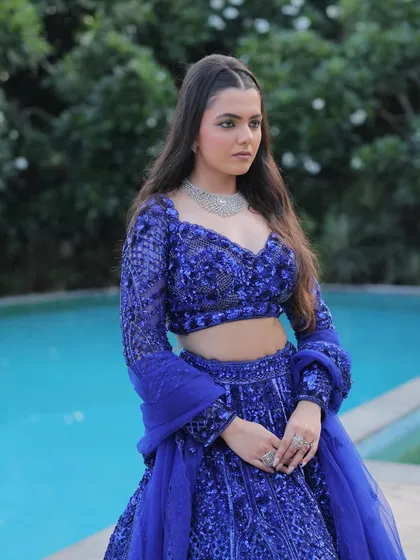 A confident pose in our electric blue designer lehenga. The rich color and intricate work make it a perfect choice for an engagement or a wedding guest look.